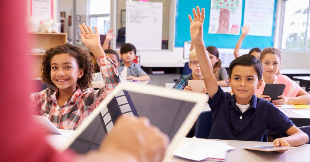 Students raising hands in class